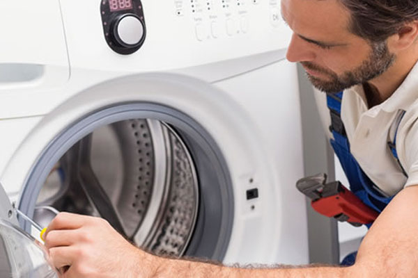 A repair technician inspecting a washing machine